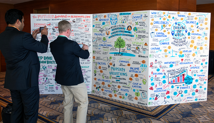 Two conference attendees take photos of a wall of visual notes / graphic recording boards